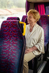 Senior woman sitting on travel bus and waiting for excursion
