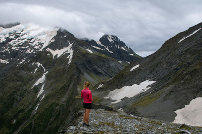 Rear view of woman standing on mountain against sky