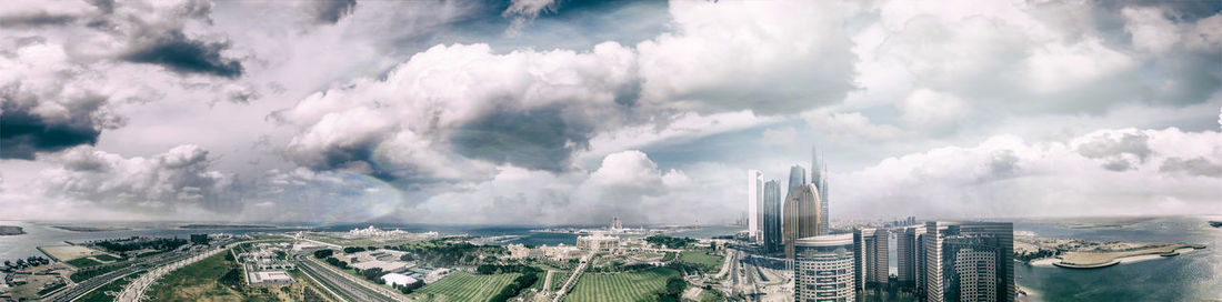 Panoramic view of buildings in city against cloudy sky