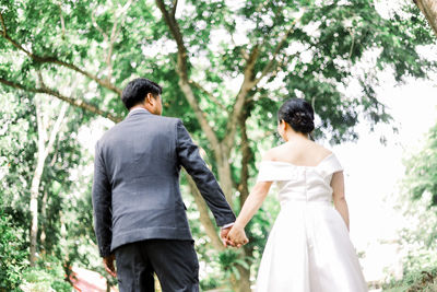 Rear view of couple standing against trees