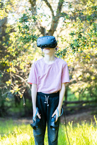Young person standing in field in front of trees with vr goggles on