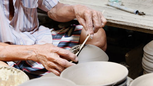 Midsection of man working on pottery wheel at workshop