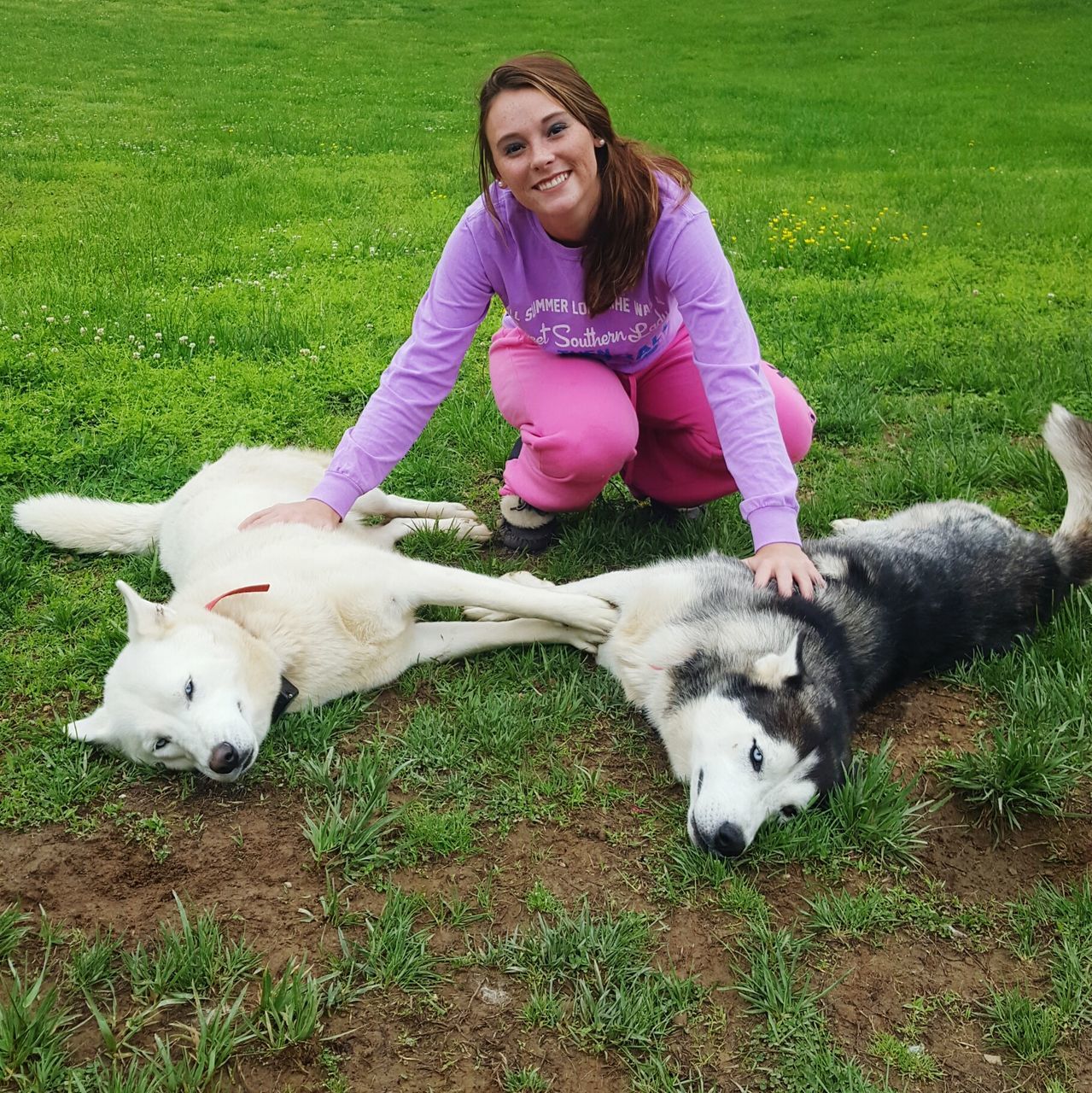 grass, domestic animals, pets, animal themes, mammal, person, field, looking at camera, dog, portrait, grassy, one animal, leisure activity, full length, lifestyles, elementary age, smiling, casual clothing