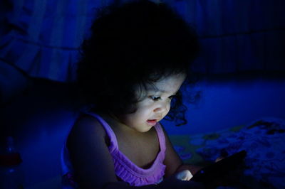 Close-up of girl using mobile phone on bed at home