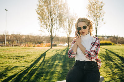 Portrait of young woman wearing sunglasses standing on field