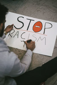 High angle view of man making signboard of racism in building