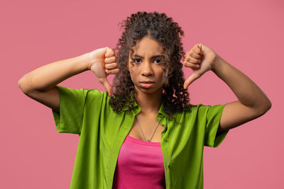 Portrait of young woman standing against yellow background