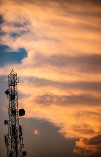 Low angle view of communications tower against cloudy sky