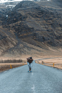 Side view of man skateboarding on road against sky