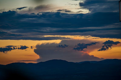 Scenic view of dramatic sky over silhouette mountains during sunset