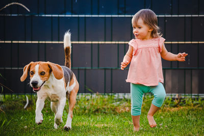 Cute girl and dog against fence at back yard