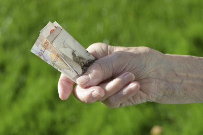 Close-up of person holding paper currency outdoors