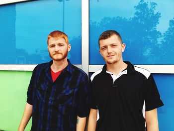 Portrait of friends standing against glass wall