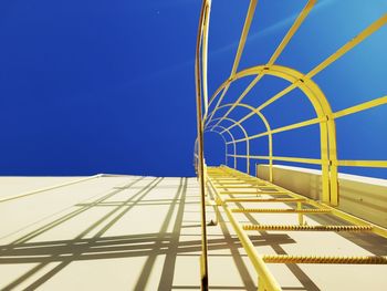 Low angle view of ladder against clear blue sky