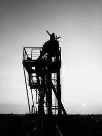 Silhouette person with arms outstretched standing on observation point against clear sky