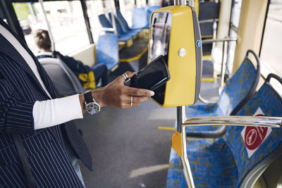 Midsection of man holding camera in bus