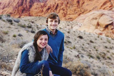 Portrait of smiling friends on rock