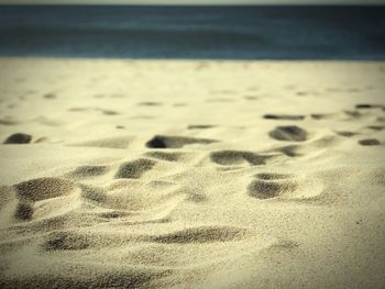 Footprints on sand at beach against sky