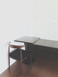 Empty chair and table by white wall