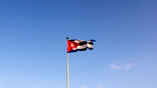 Low angle view of cuban flag against clear blue sky