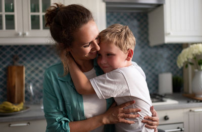 Happy mother hugging son in kitchen