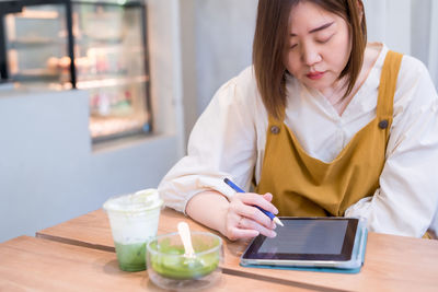 Woman using digital tablet while sitting at cafe