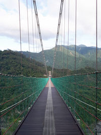 Footbridge over mountain against sky