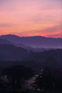 Scenic view of silhouette mountains against romantic sky at sunset