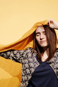 Young woman with yellow scarf against wall