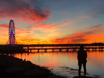 Silhouette woman standing at beach against sky during sunset