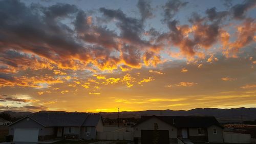 Silhouette of house against cloudy sky at sunset
