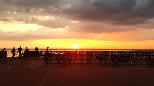 People on beach against sky during sunset