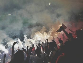 Crowd burning crackers in soccer stadium at night