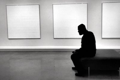 Side view of silhouette man sitting in museum