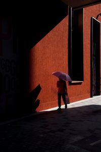 Full length of man walking on footpath against building