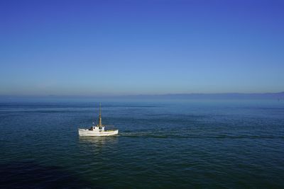 Sailboat sailing in sea against clear blue sky