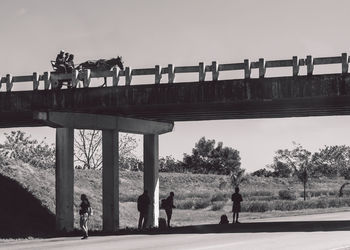 People walking on bridge against clear sky