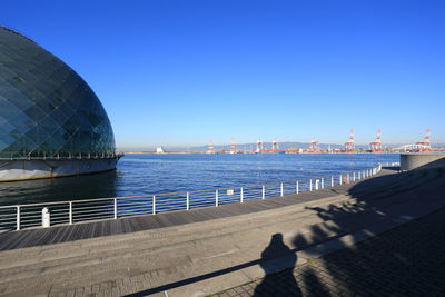 View of city by sea against clear blue sky