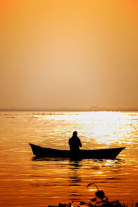 Silhouette man in sea against sky during sunset