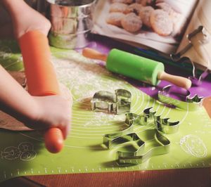 Cropped hands of woman rolling dough in kitchen