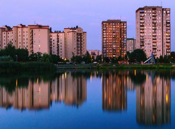 Reflection of buildings in lake against sky at dusk