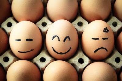 Close-up of anthropomorphic faces on eggs in carton