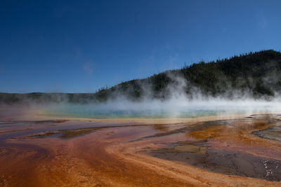 Geyser at yellowstone national park against cloudy sky