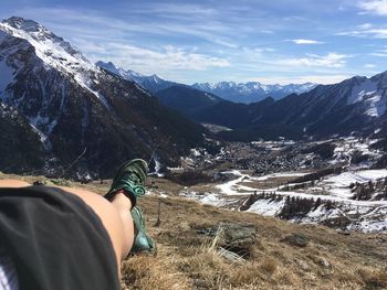 Low section of person on snowcapped mountains against sky