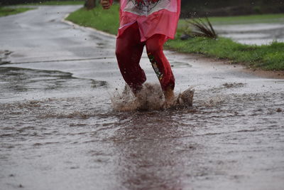 Low section of man standing in puddle