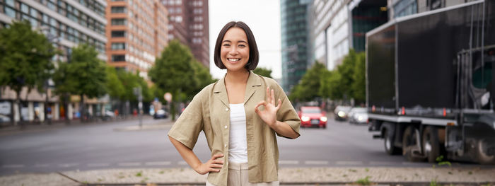 Portrait of young woman standing in city