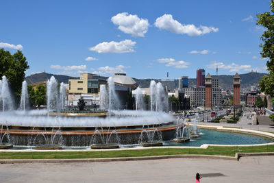 Fountain in city against sky