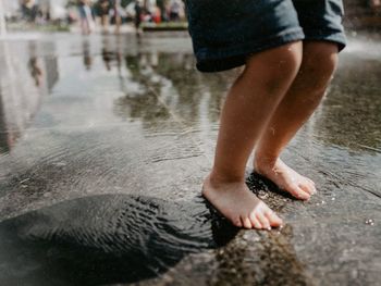 Low section of boy standing on wet footpath