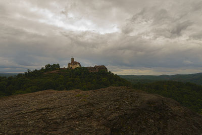 Building on mountain against cloudy sky