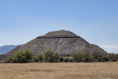 Built structure on field against clear blue sky